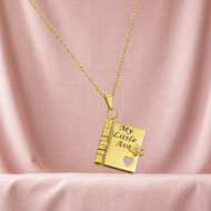 Gold heart notebook pendant engraved with My Little Ava against blush linen